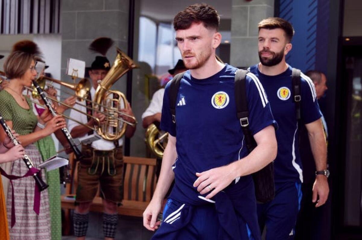 Scotland captain Andy Robertson walks out of the team hotel as a Bavarian band plays in the background