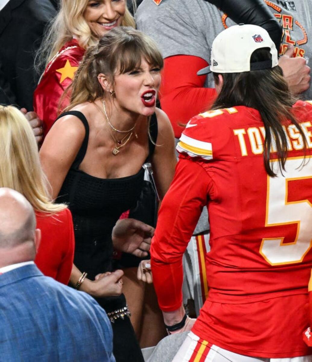 Taylor Swift in black top speaking to Kansas City Chiefs player in red jersey