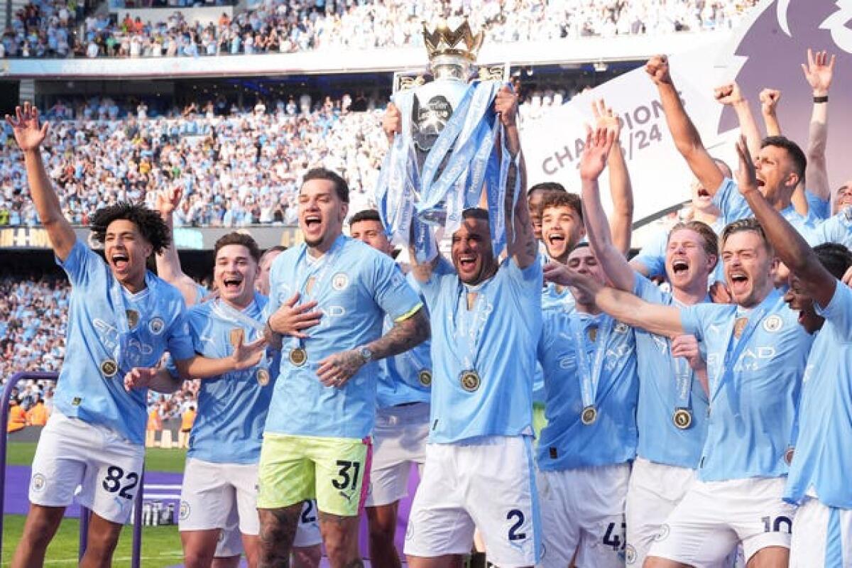 Manchester City skipper Kyle Walker, centre, lifts the Premier League trophy as the team celebrate