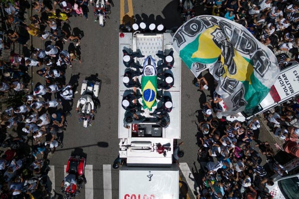 The coffin of late Brazilian football great Pele is draped in the Brazilian and Santos FC soccer club flags as his remains are transported from Vila Belmiro stadium, where he laid in state, to the cemetery during his funeral procession in Santos, Brazil