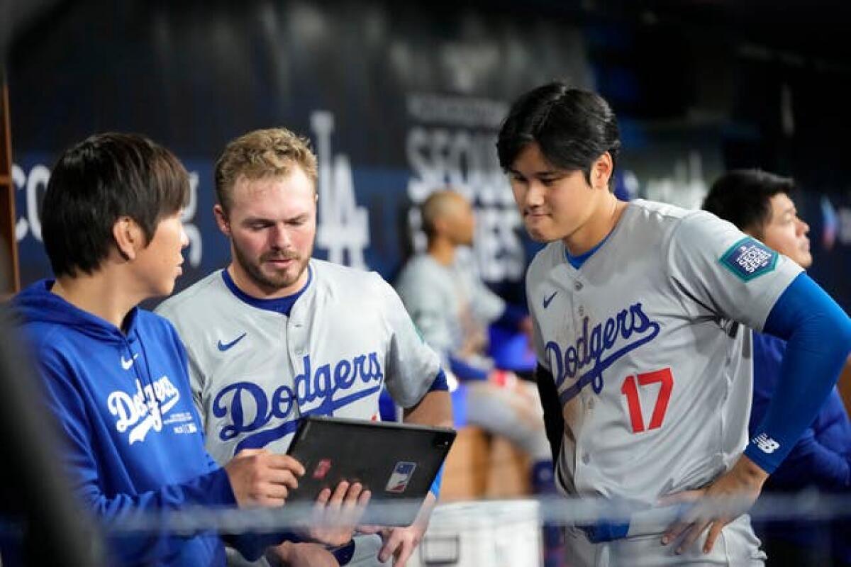 Los Angeles Dodgers’ Gavin Lux, centre, and Shohei Ohtani, right, talk with interpreter Ippei Mizuhara during the first inning of an opening day baseball game against the San Diego Padres at the Gocheok Sky Dome in Seoul, South Korea, on March 20