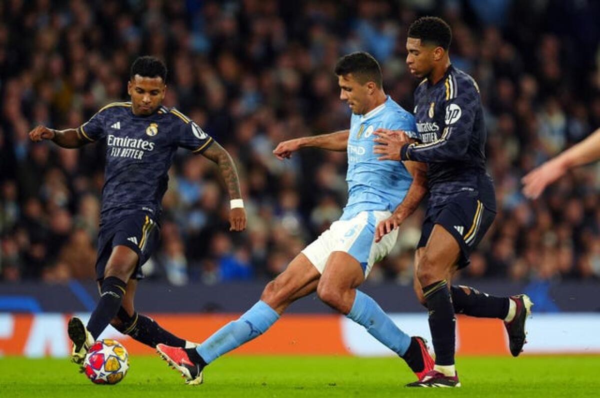 Manchester City’s Rodri (centre) is challenged by Jude Bellingham