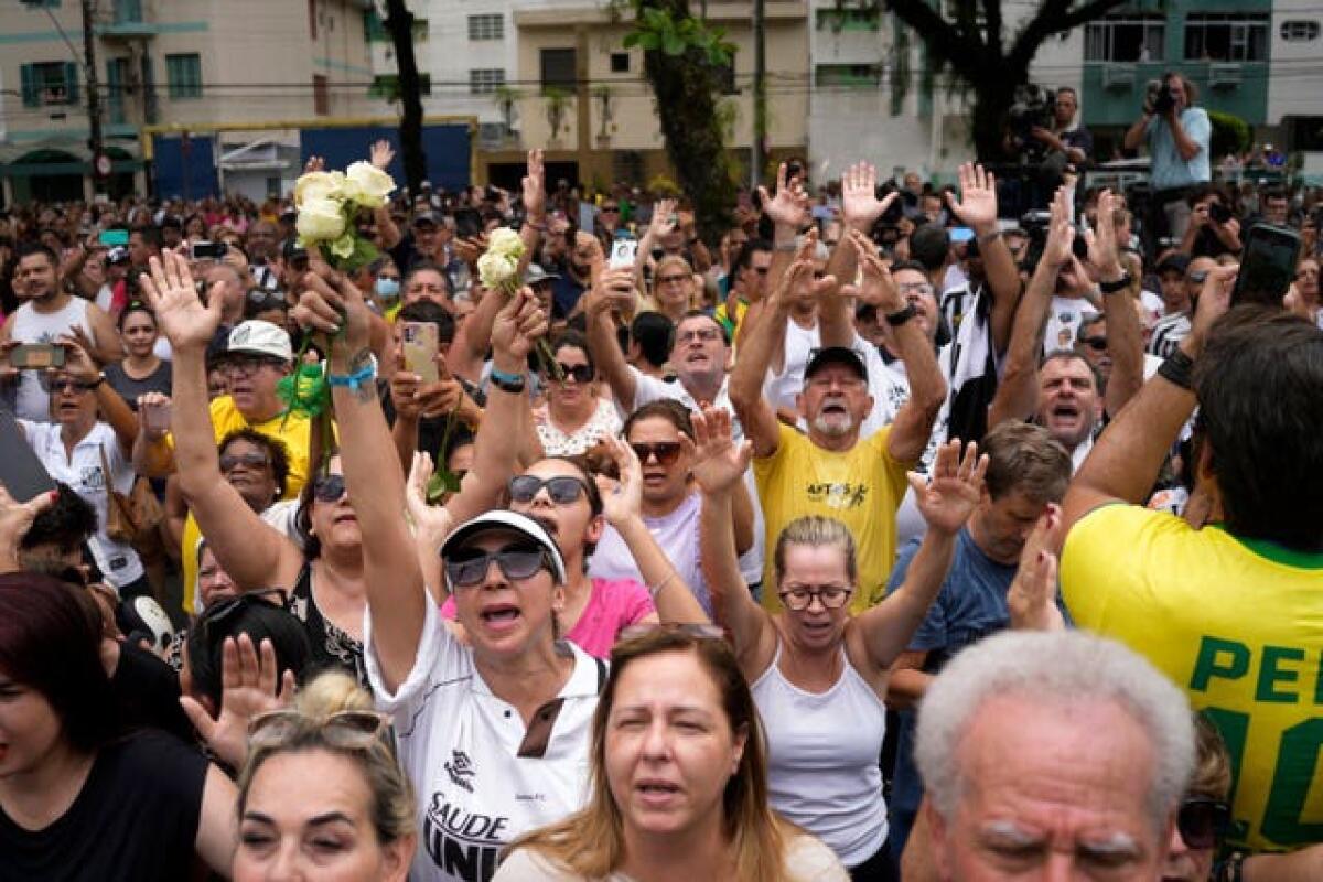 People pray outside the home of the mother of Brazilian footballer Pele during his funeral procession from Vila Belmiro stadium, where he laid in state, to the cemetery in Santos, Brazil 